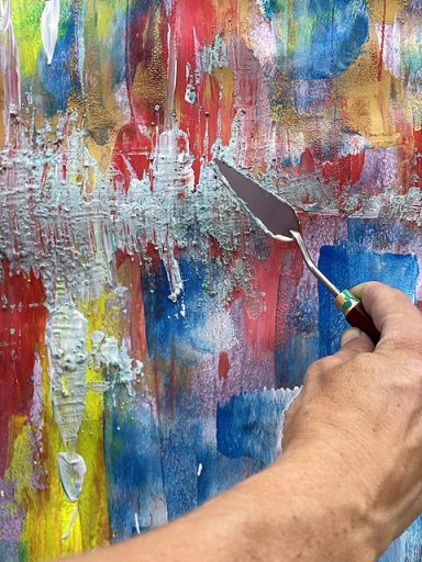 Maennliche Hand malt ein abstraktes Bild mit Spatel